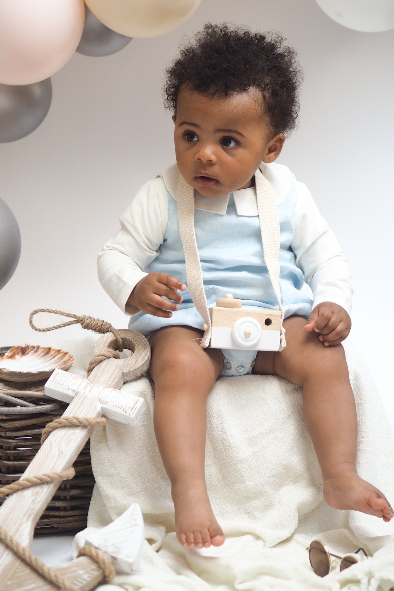 baby boy in ivory bodysuit and blue linen romper